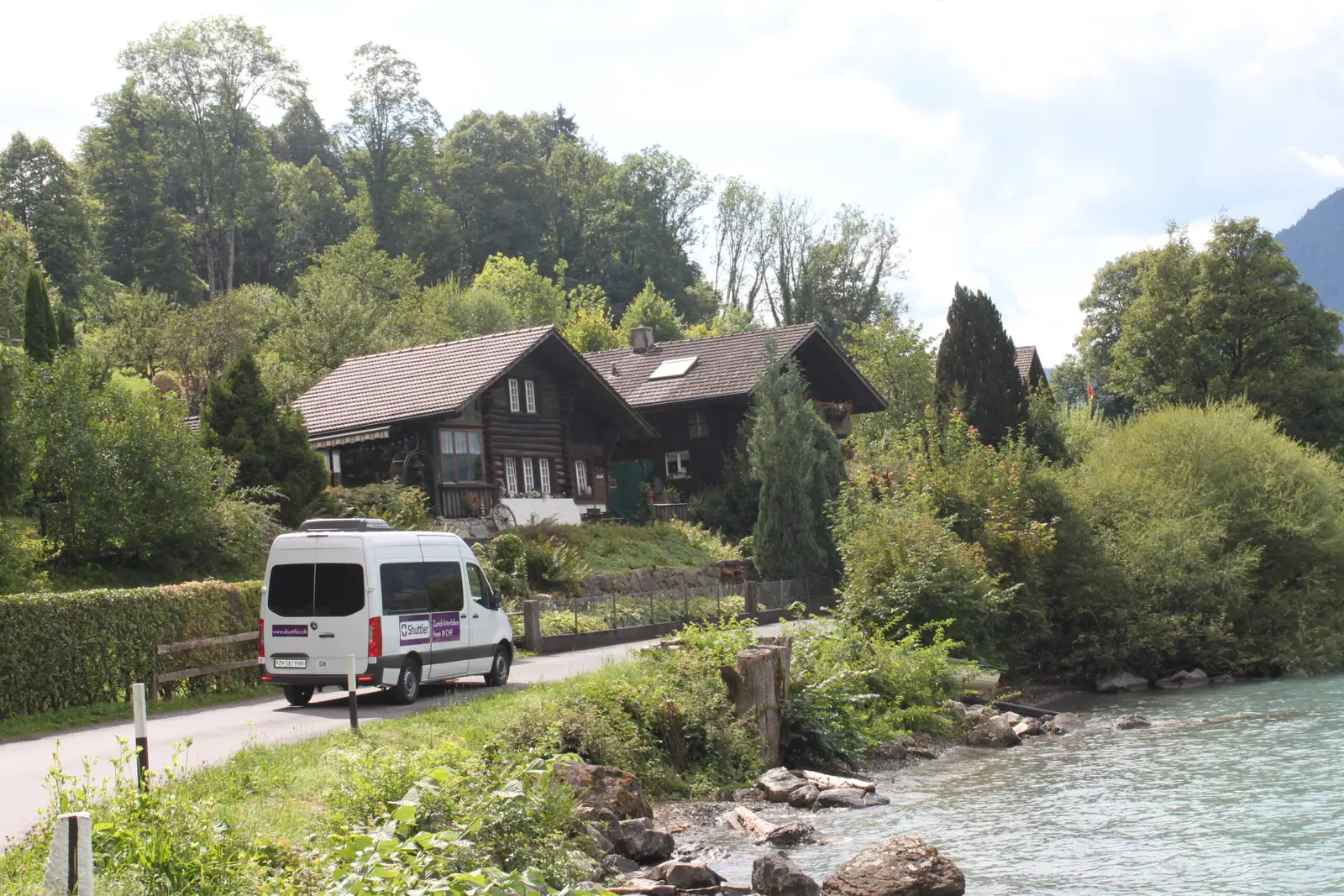 A Shuttler minibus travelling along a Swiss lake