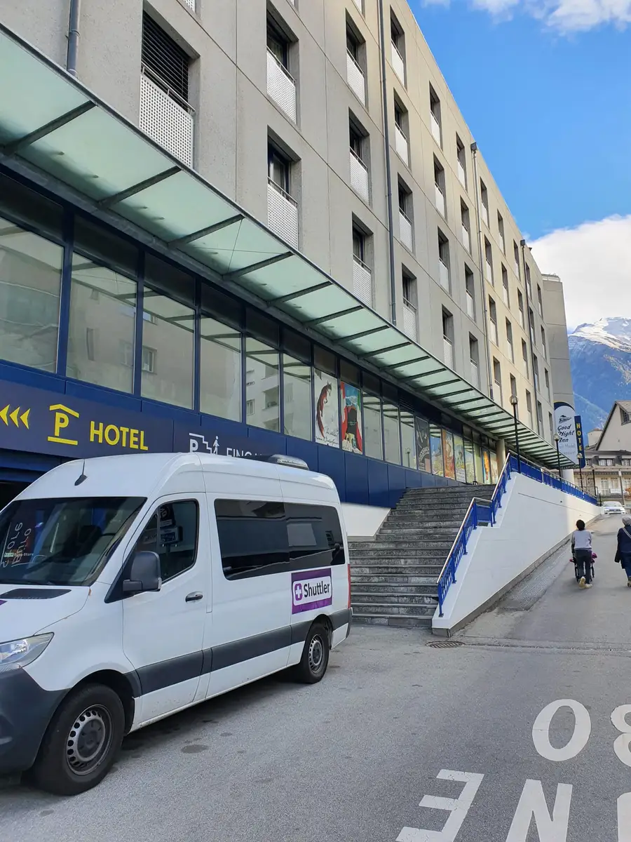 A Shuttler minibus picking up guests at a hotel door