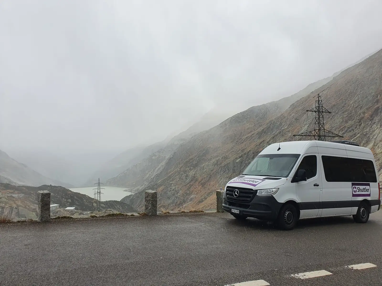 A Shuttler minibus on an alpine road in the fog